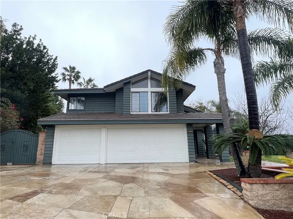 a view of a house with a yard and palm trees