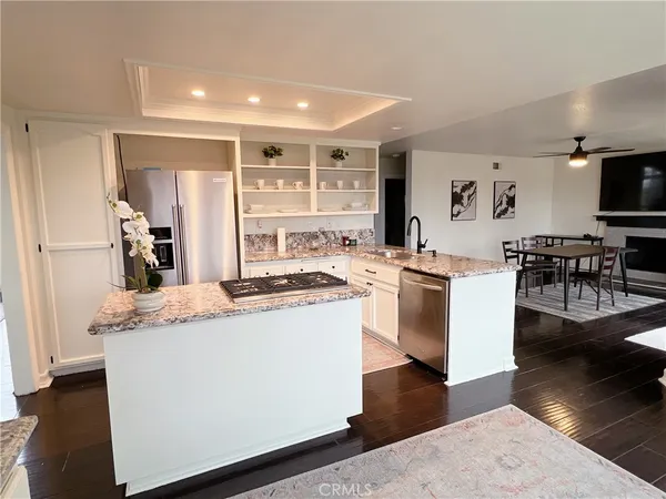 a kitchen with stainless steel appliances granite countertop a refrigerator a stove and a dining table with wooden floor