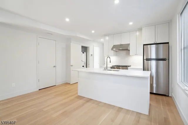 a kitchen with white cabinets and refrigerator