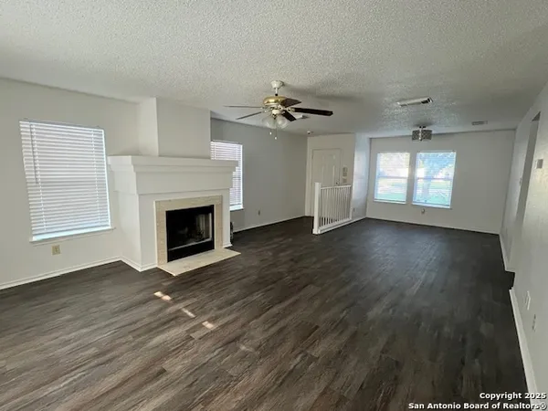 an empty room with wooden floor fireplace and windows