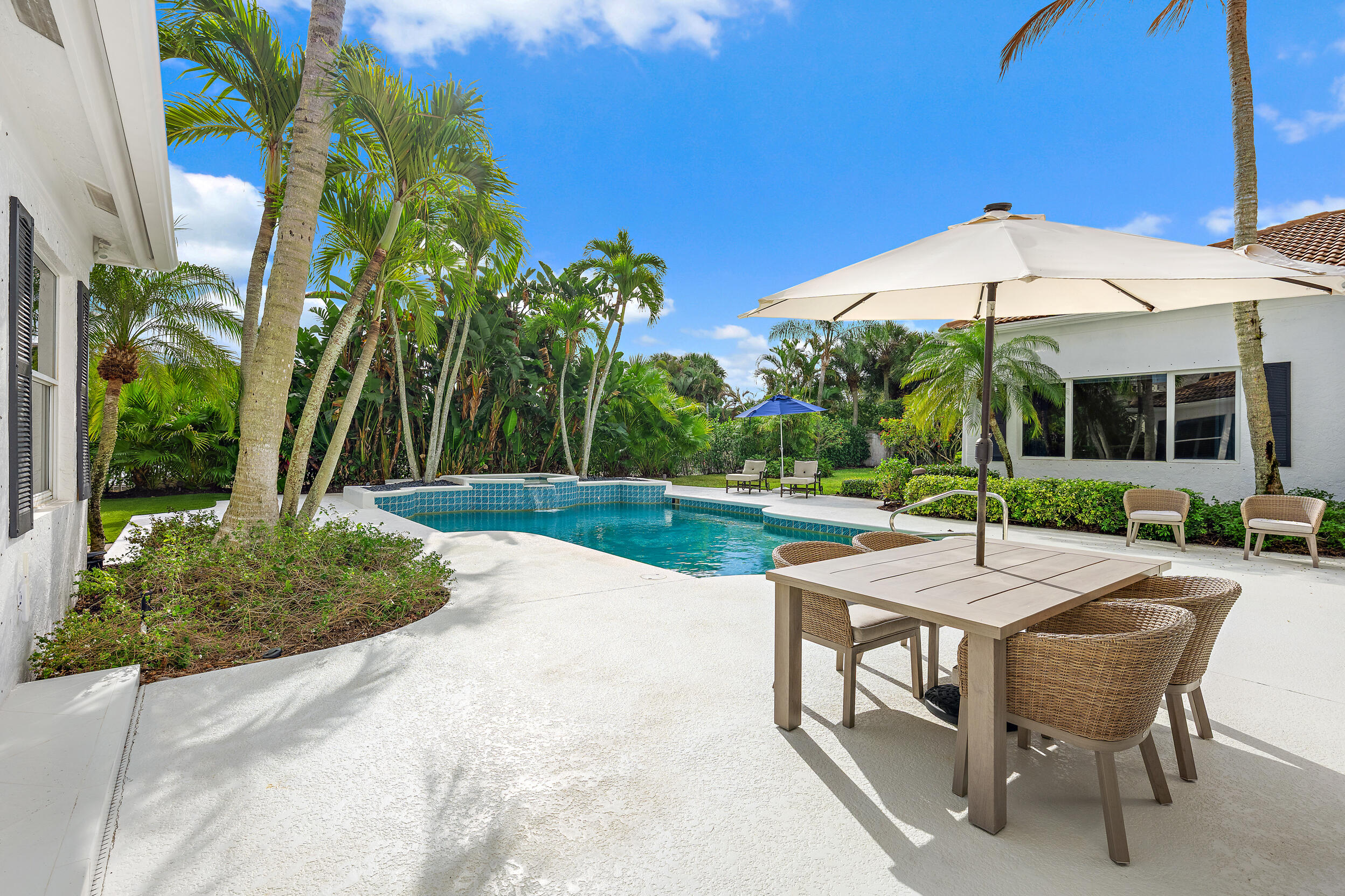 325 Eagle Drive Jupiter, FL 33477 - Photo 2 of 48 a patio with a table and chairs under an umbrella