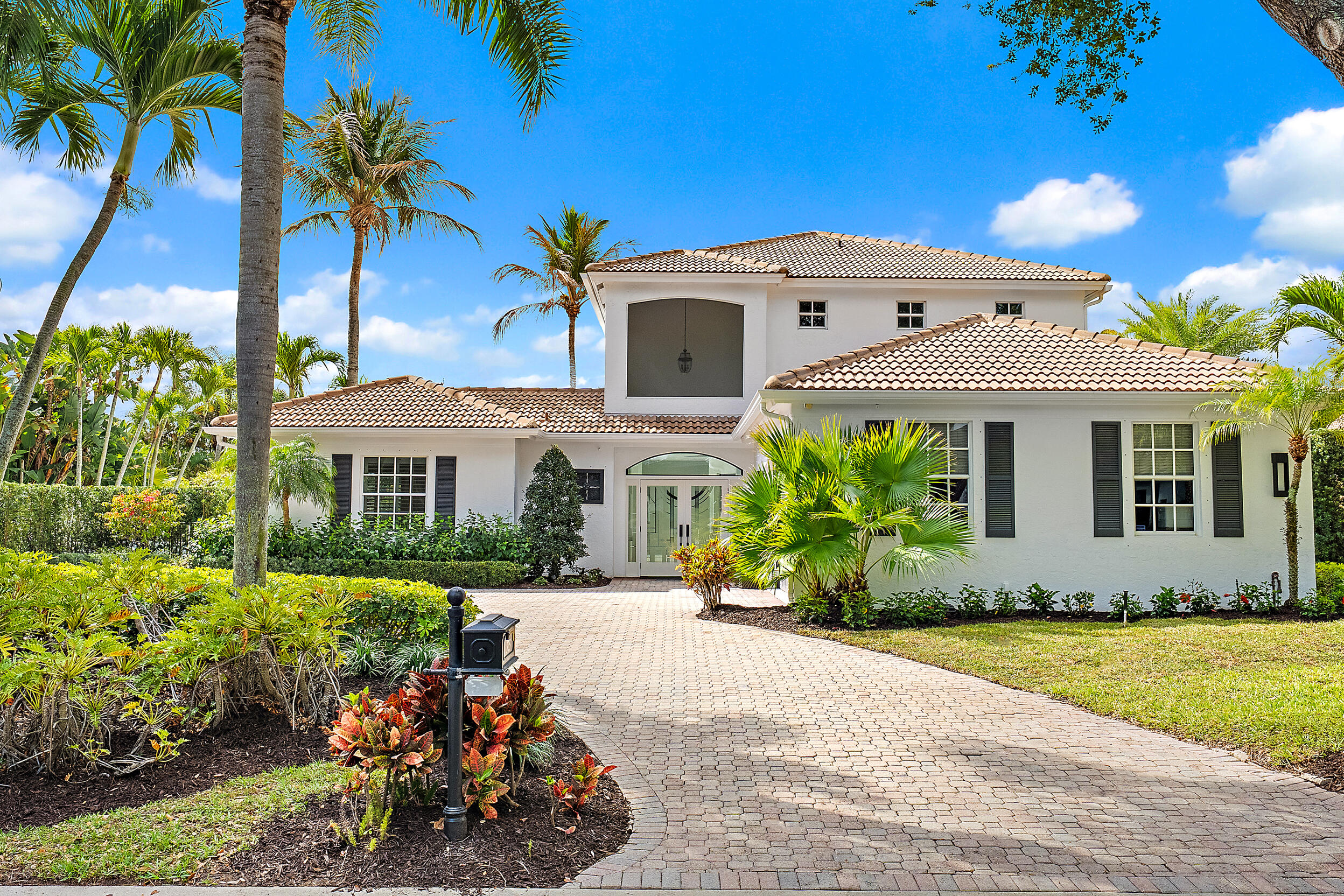 325 Eagle Drive Jupiter, FL 33477 - Photo 4 of 48 a front view of a house with a yard and a garden