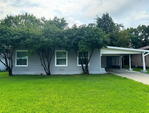 a view of a house with a yard and a large tree