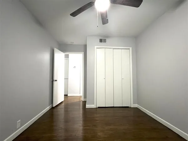 an empty room with wooden floor chandelier fan and windows
