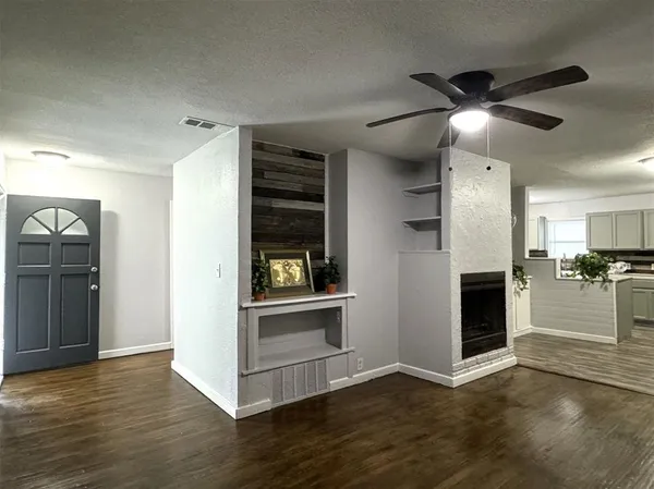 an empty room with wooden floor fireplace and windows