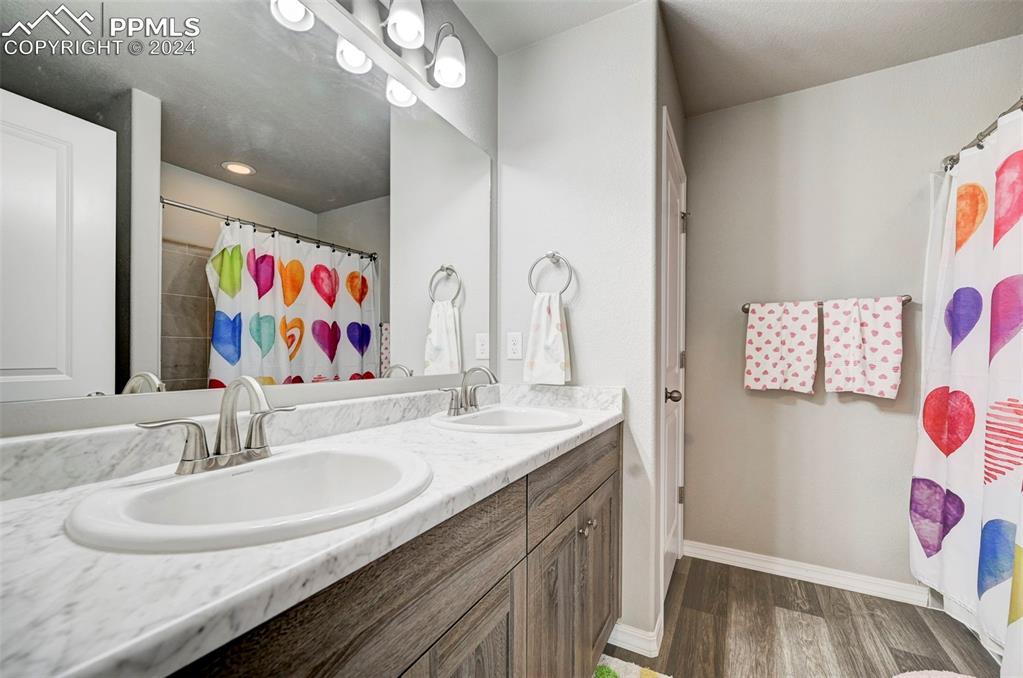 4472 Gneiss Loop Colorado Springs, CO 80938 - Photo 26 of 30 a bathroom with a sink double vanity mirror and glass door