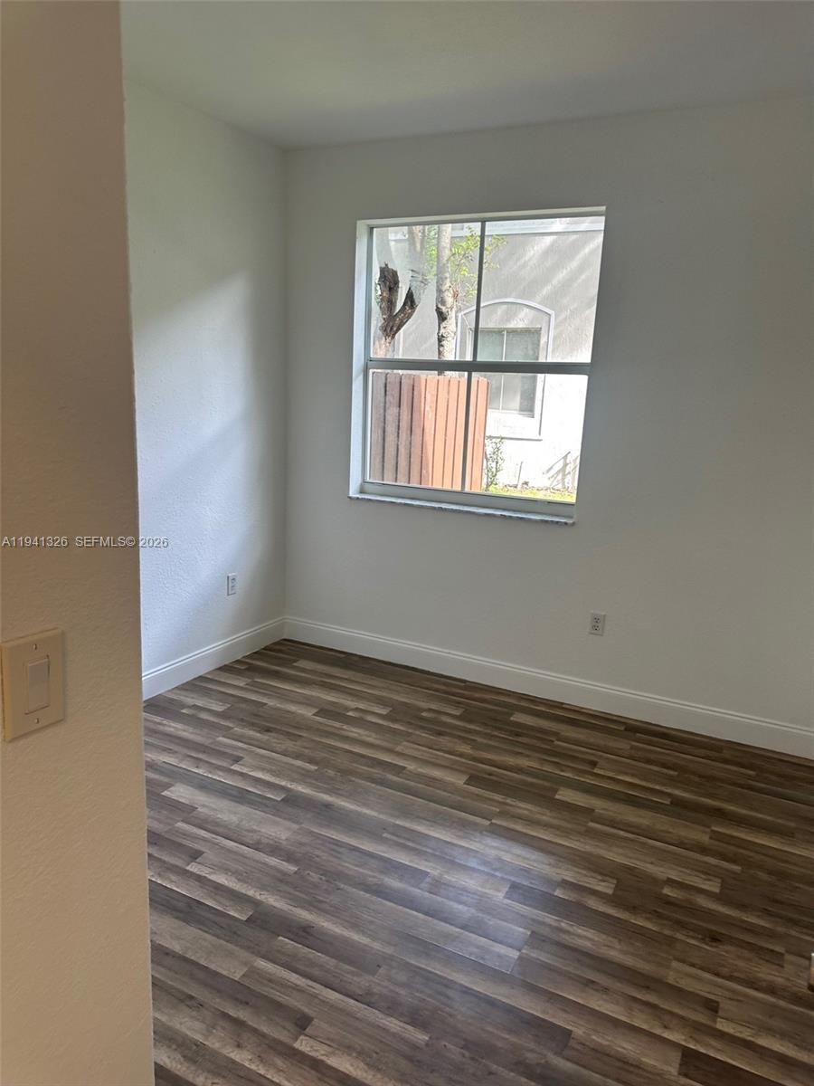 1663 Southeast 27th Drive, Unit 102 Homestead, FL 33035 - Photo 15 of 18 a view of an empty room with wooden floor and a window