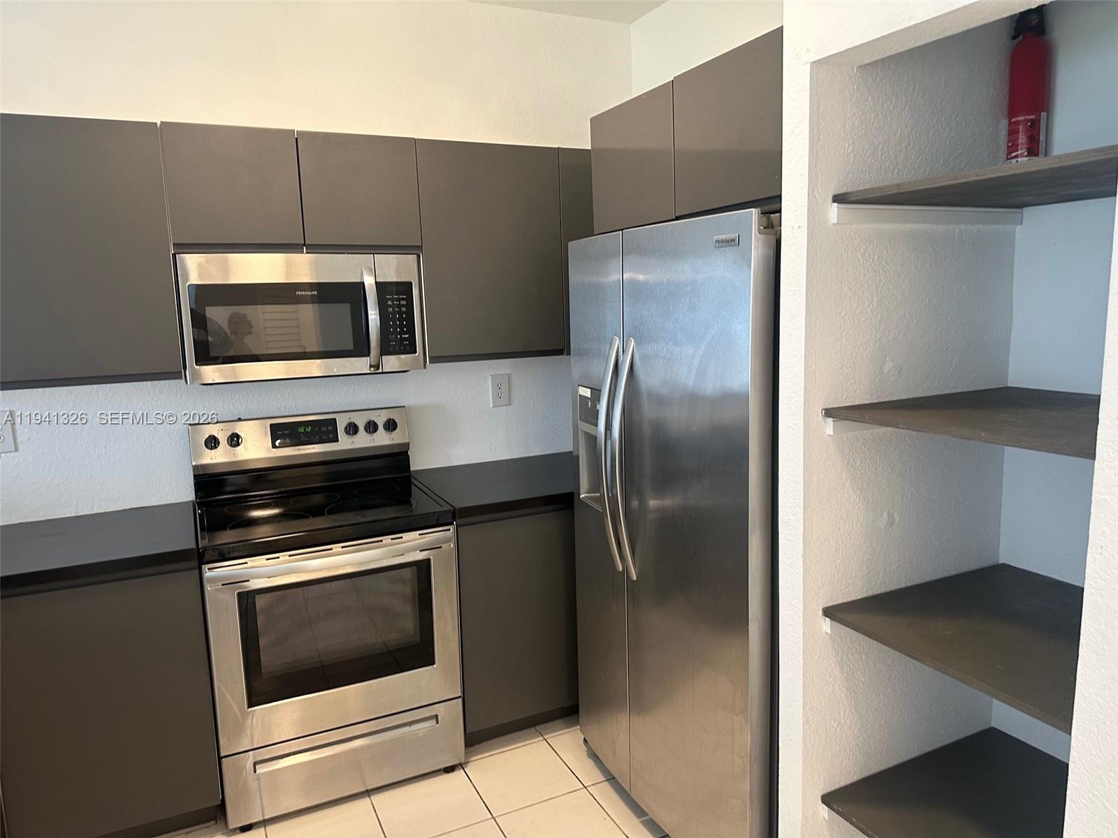 1663 Southeast 27th Drive, Unit 102 Homestead, FL 33035 - Photo 7 of 18 a kitchen with a refrigerator stove and microwave
