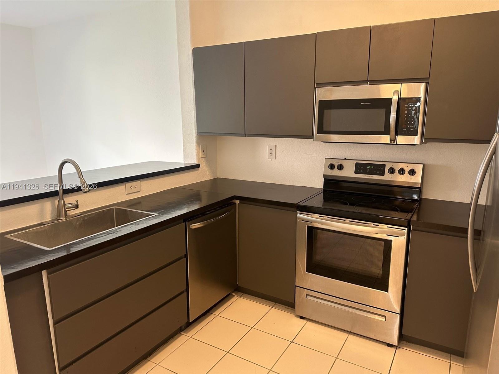 1663 Southeast 27th Drive, Unit 102 Homestead, FL 33035 - Photo 8 of 18 a kitchen with a sink stove and microwave