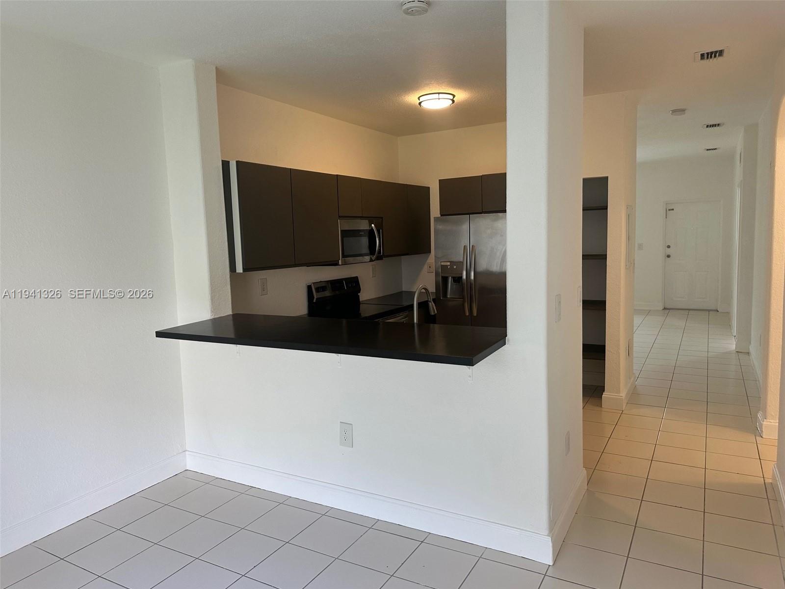 1663 Southeast 27th Drive, Unit 102 Homestead, FL 33035 - Photo 10 of 18 a hallway with cabinets and stainless steel appliances
