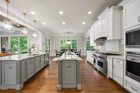 a kitchen with stainless steel appliances granite countertop a stove top oven a sink dishwasher a dining table and chairs with wooden floor