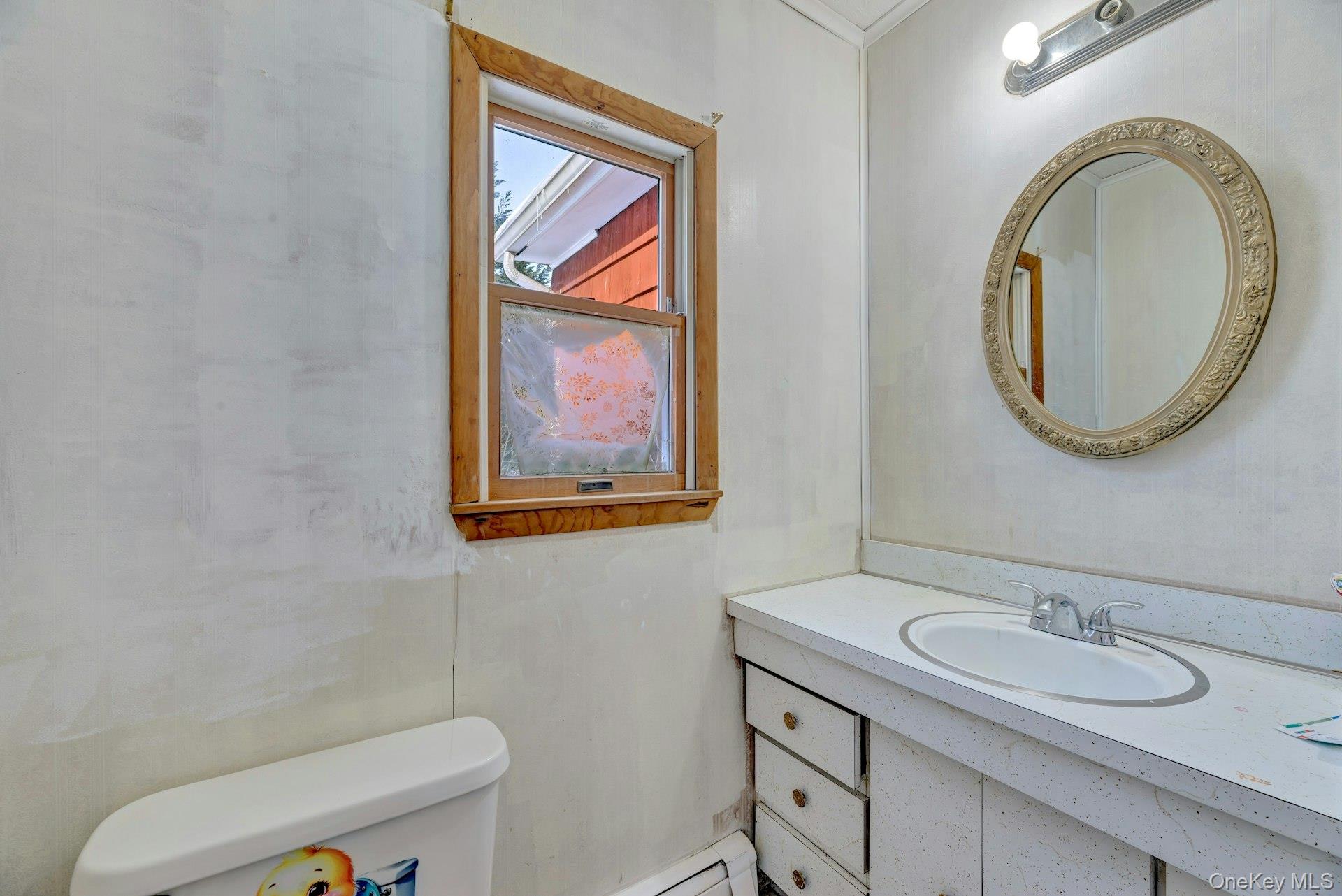 32 Stackyard Drive Mastic Beach, NY 11951 - Photo 16 of 25 a bathroom with a toilet a sink and mirror