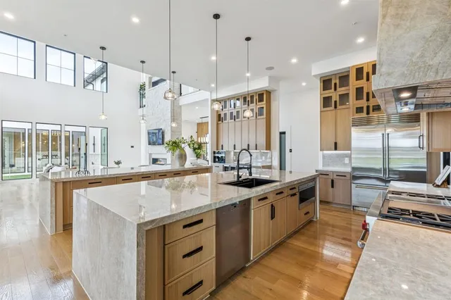 a large kitchen with kitchen island a large counter top space a sink stainless steel appliances and cabinets