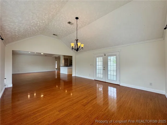 a view of a room with wooden floor chandelier and windows