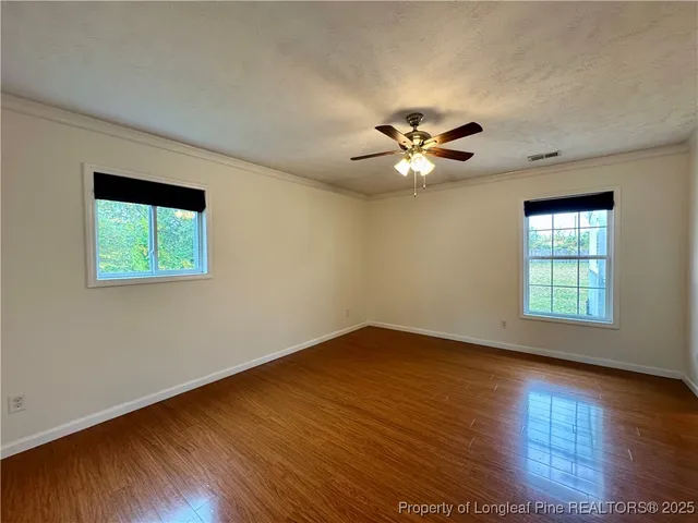 a view of an empty room with window and wooden floor