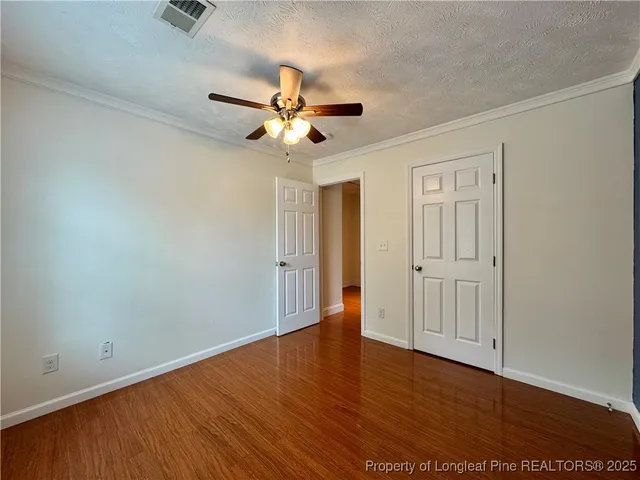 an empty room with wooden floor fan and windows