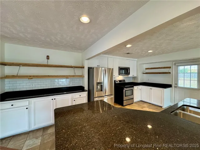 a kitchen with stainless steel appliances kitchen island granite countertop a stove and a sink
