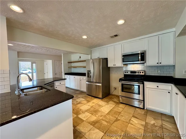 a kitchen with granite countertop a refrigerator and a stove top oven