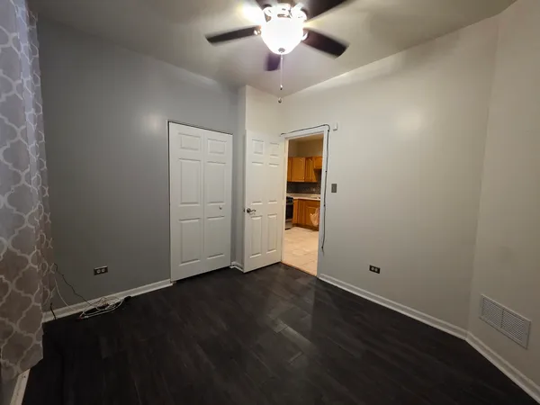 an empty room with wooden floor closet and windows