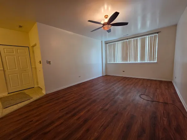 a view of empty room with wooden floor and fan
