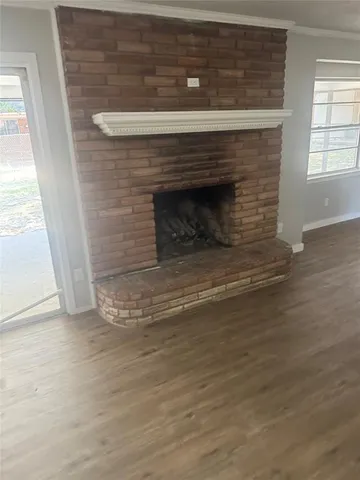 a view of empty room with wooden floor and a fireplace