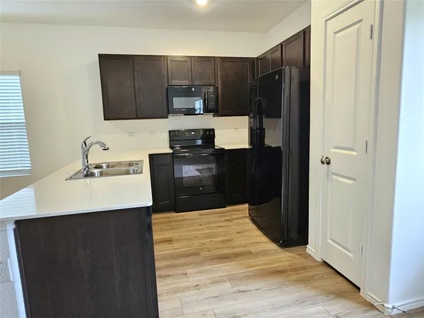 a kitchen with a sink a stove top oven and refrigerator