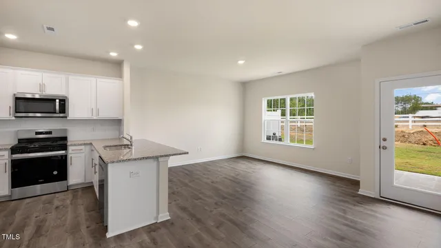 a kitchen with granite countertop a stove a sink a refrigerator and a microwave