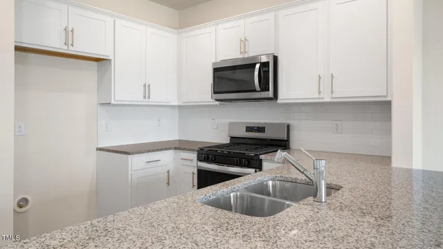 a kitchen with stainless steel appliances granite countertop a sink stove and microwave