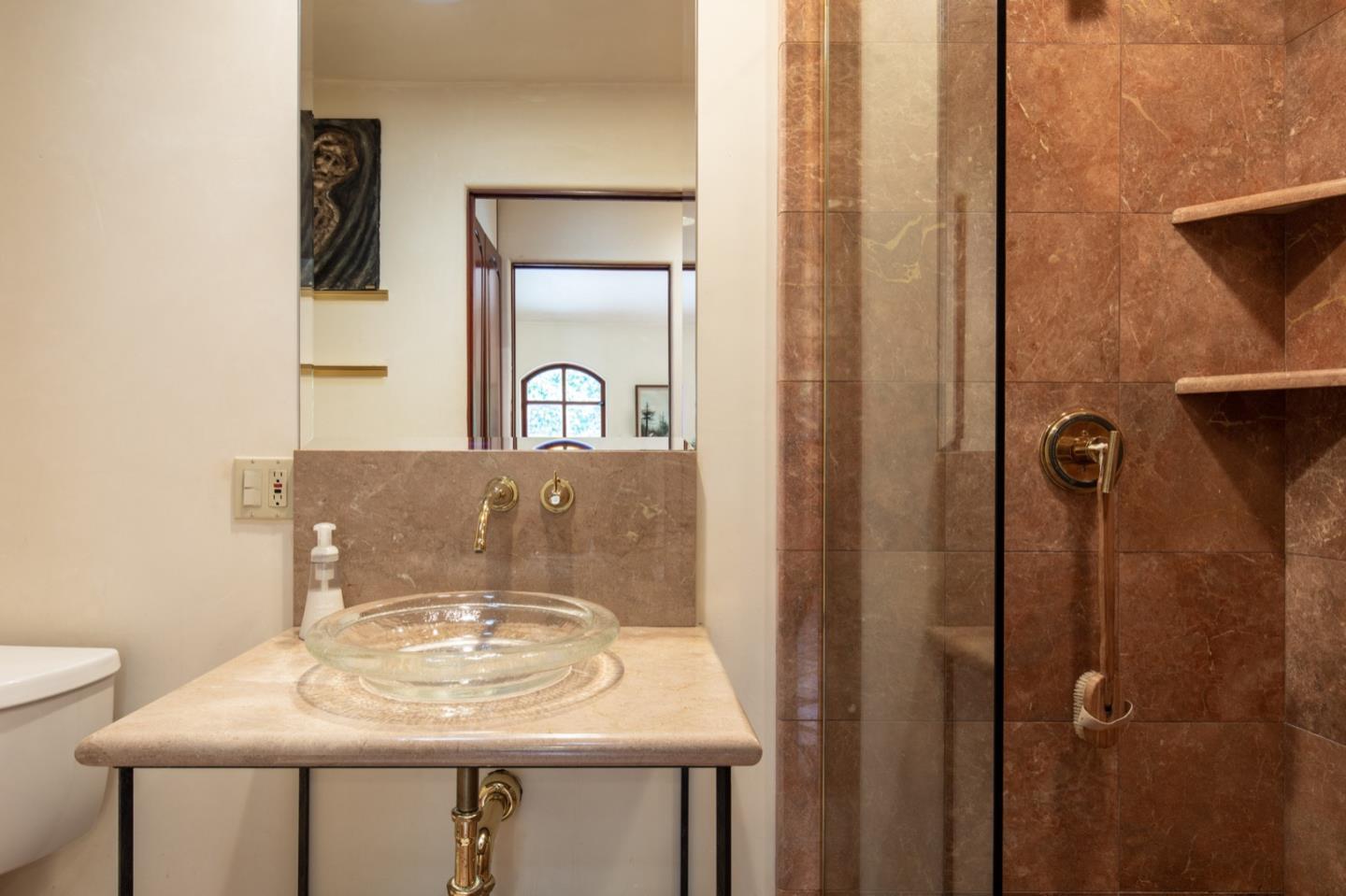 1007 Ocean Road Pebble Beach, CA 93953 - Photo 17 of 24 a bathroom with a sink a mirror and shower