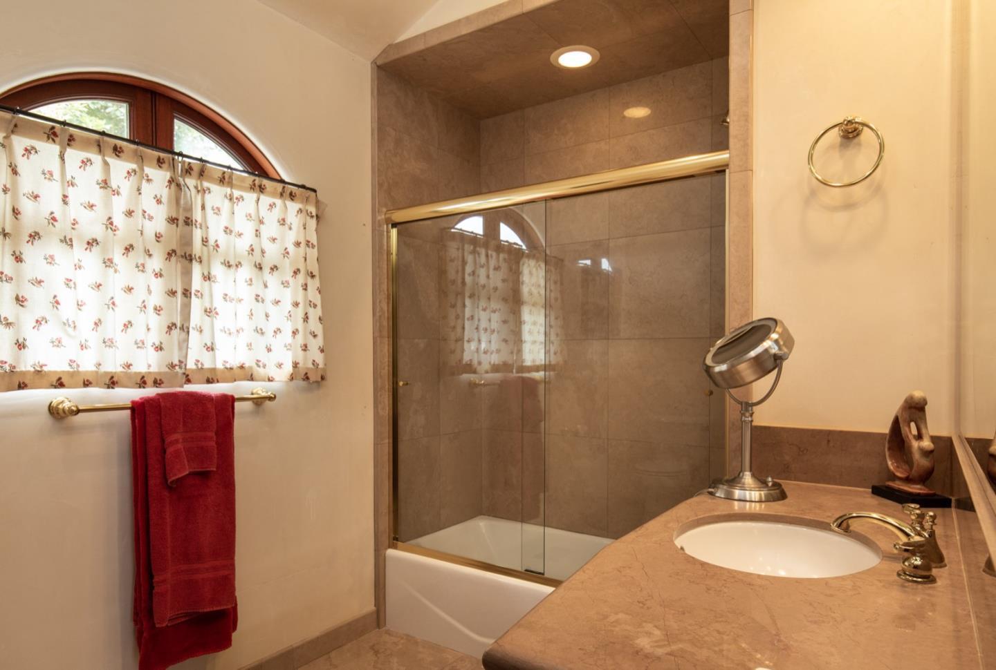 1007 Ocean Road Pebble Beach, CA 93953 - Photo 23 of 24 a bathroom with a sink a mirror and a shower