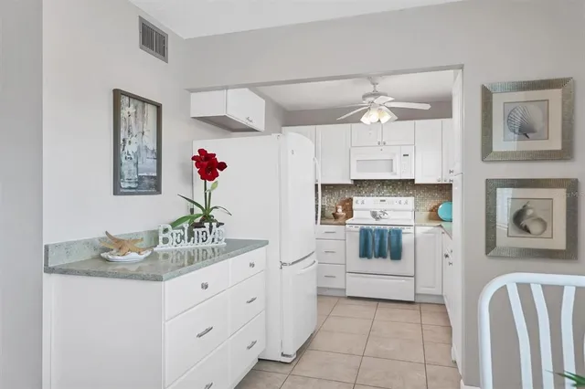 a kitchen with granite countertop white cabinets and white appliances