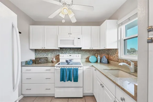a kitchen with granite countertop a sink a stove and cabinets