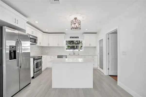 a kitchen with kitchen island white cabinets and stainless steel appliances