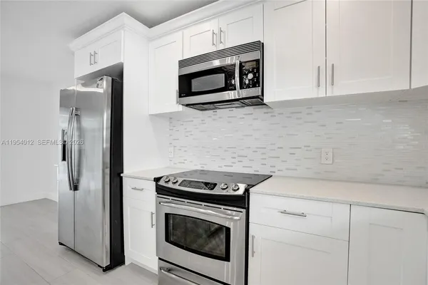 a kitchen with stainless steel appliances granite countertop white cabinets a microwave oven and a refrigerator