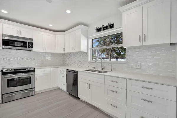 a kitchen with white cabinets stainless steel appliances and sink