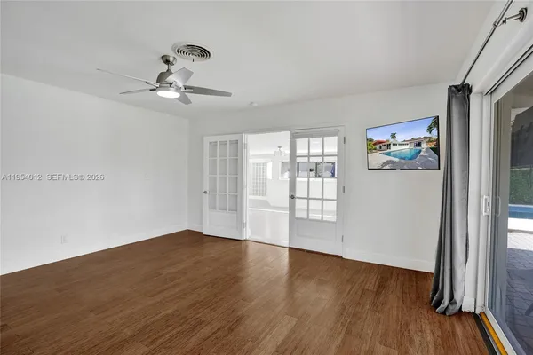 a view of an empty room with wooden floor and a window