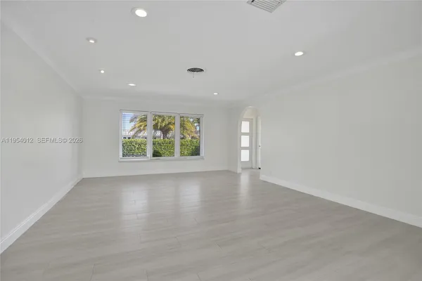 a view of an empty room with a window and wooden floor