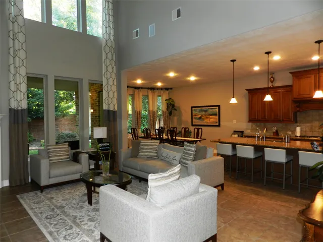 a living room with couches a coffee table and kitchen view with wooden floor