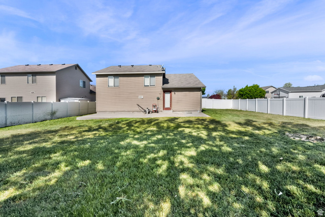 2575 Athena Drive Magna, UT 84044 - Photo 22 of 23 Expansive backyard featuring a large green lawn, concrete patio, and full perimeter white vinyl fencing