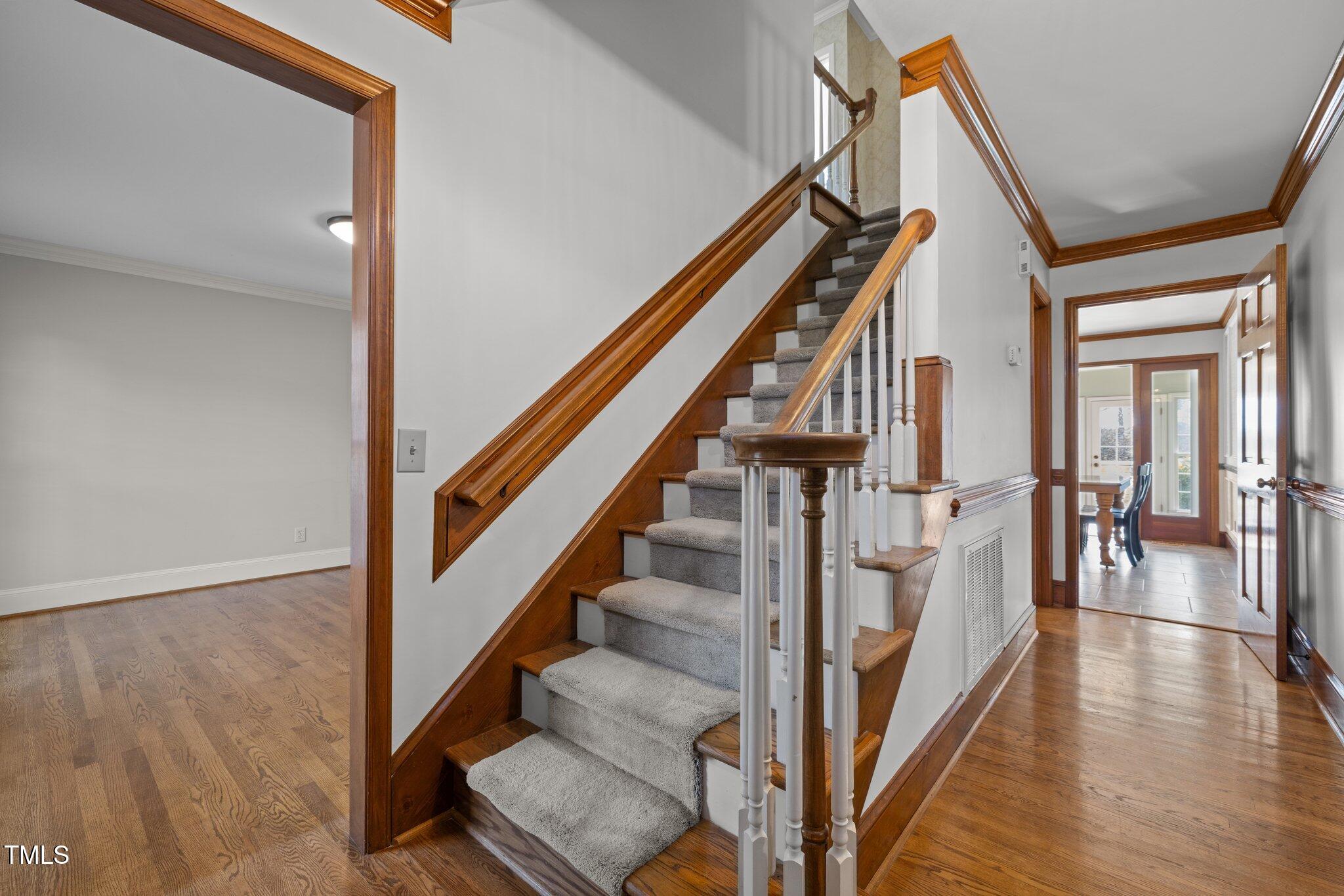 7205 Penny Road Raleigh, NC 27606 - Photo 3 of 50 a view of staircase with lots of frames on wall and wooden floor