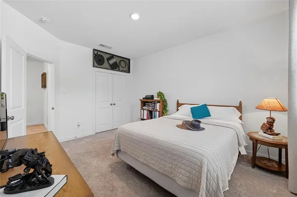 a bedroom with bed and a lamp on dresser
