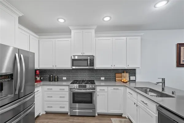 a kitchen with granite countertop white cabinets and stainless steel appliances
