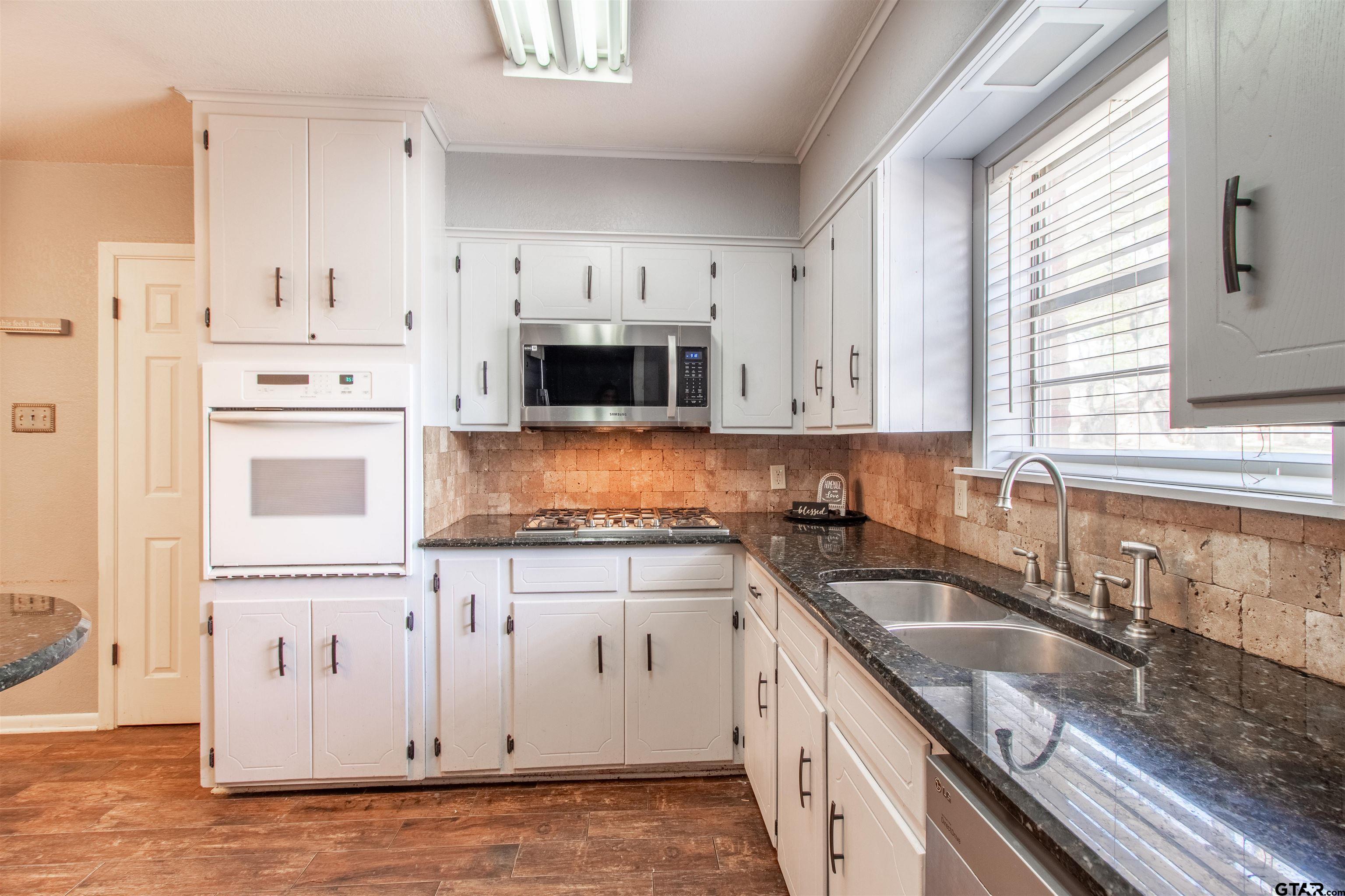 727 Oxford Drive Tyler, TX 75703 - Photo 11 of 33 a kitchen with granite countertop a sink a stove a microwave and cabinets