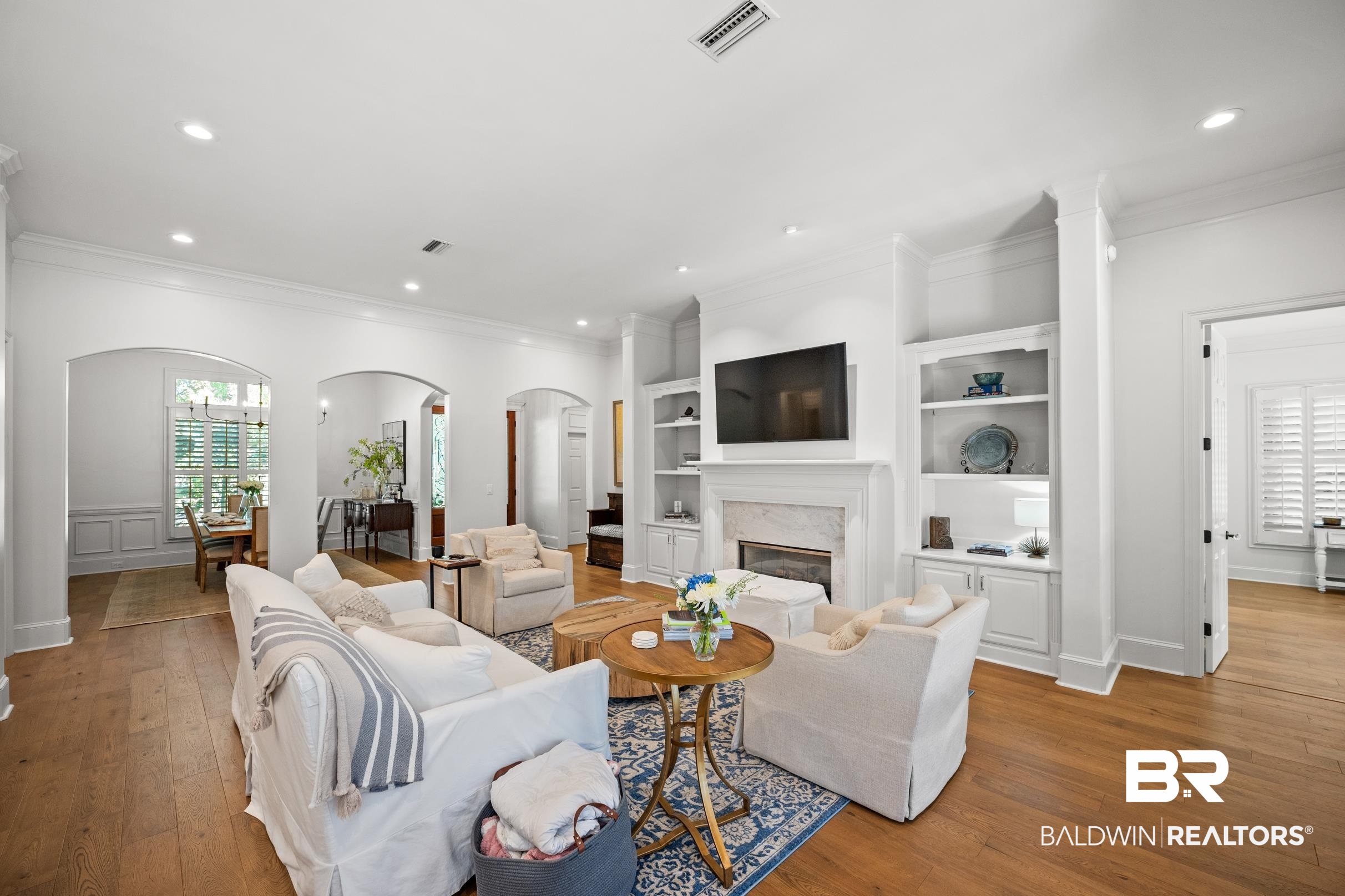 115 Sandy Ford Road Fairhope, AL 36532 - Photo 23 of 47 Living room featuring arched walkways, light wood-style flooring, recessed lighting, a premium fireplace, and crown molding