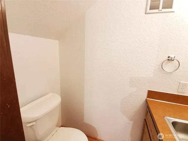 a white toilet sitting next to a white wall