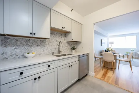 a kitchen with white cabinets and sink
