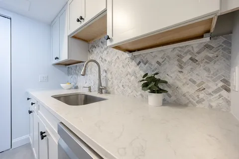 a kitchen with a sink and a stove with wooden floor