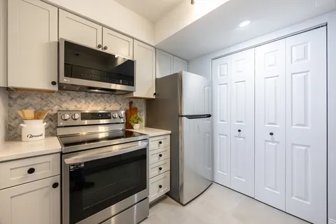 a kitchen with stainless steel appliances white cabinets white stove a microwave and a refrigerator