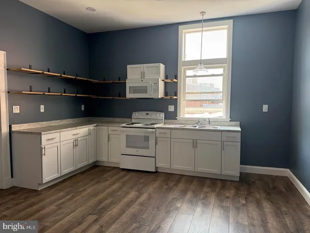 a kitchen with granite countertop white cabinets and white appliances
