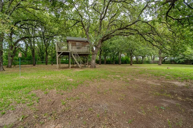 a view of a house with a big yard and large trees
